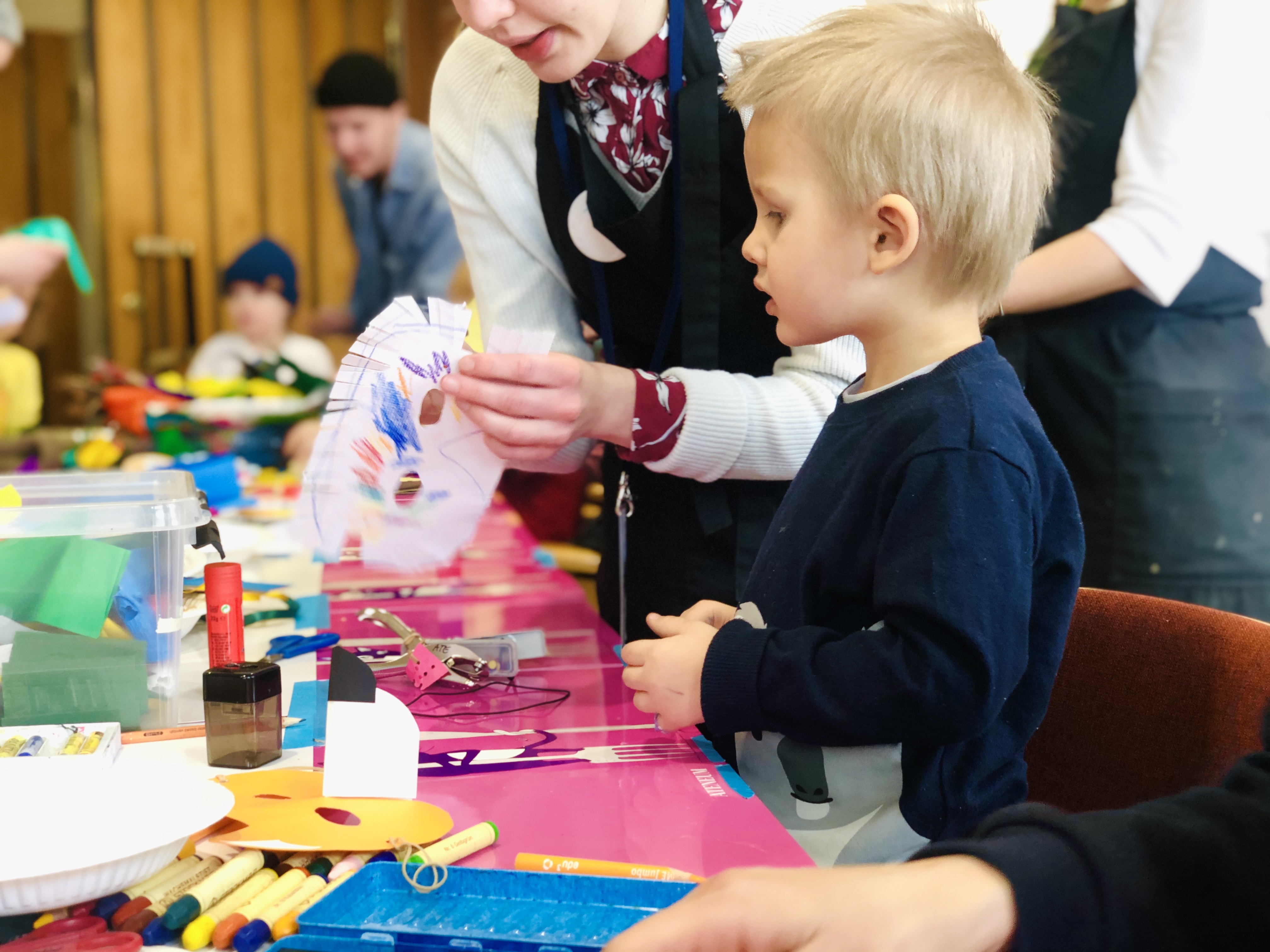 En ung, blond pojke pysslar vid ett bord.