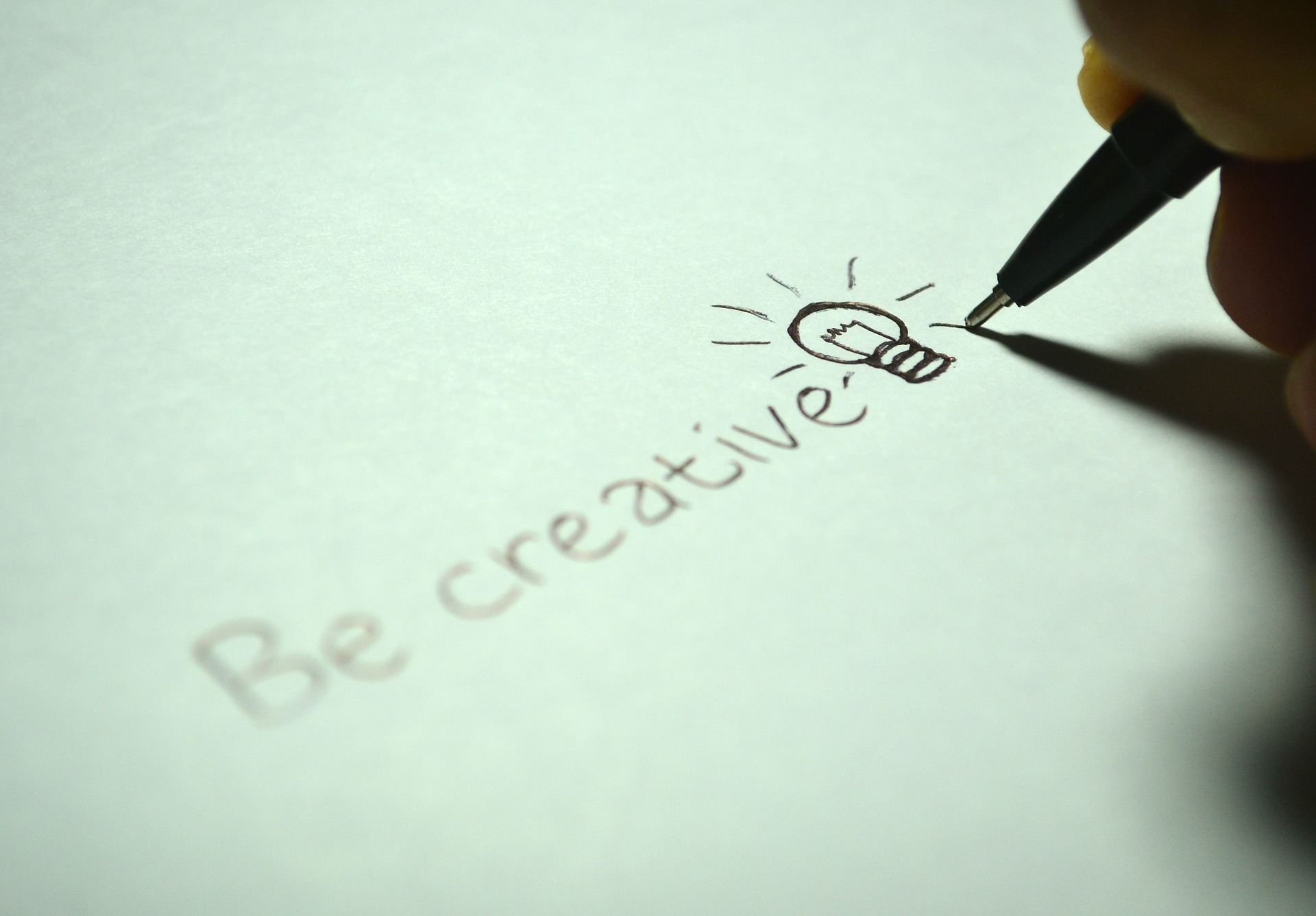 "Be creative"-text med en ritad glödlampa på papper.