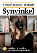 Ung kvinna med mörkt hår sitter vid en bokhylla med hörlurar på.