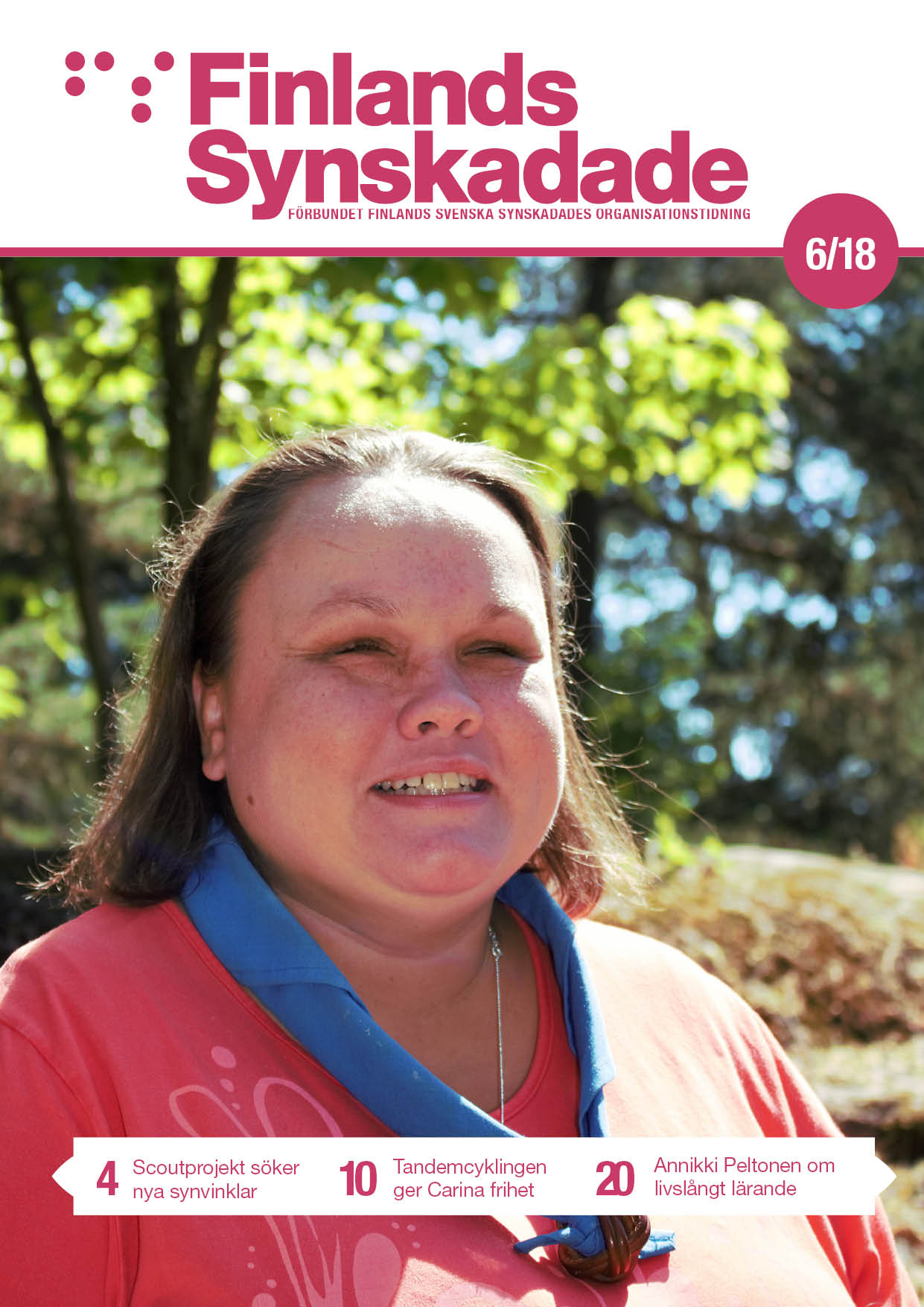 En brunhårig kvinna står i solskenet med en scouthalsduk runt halsen och gröna träd syns i bakgrunden