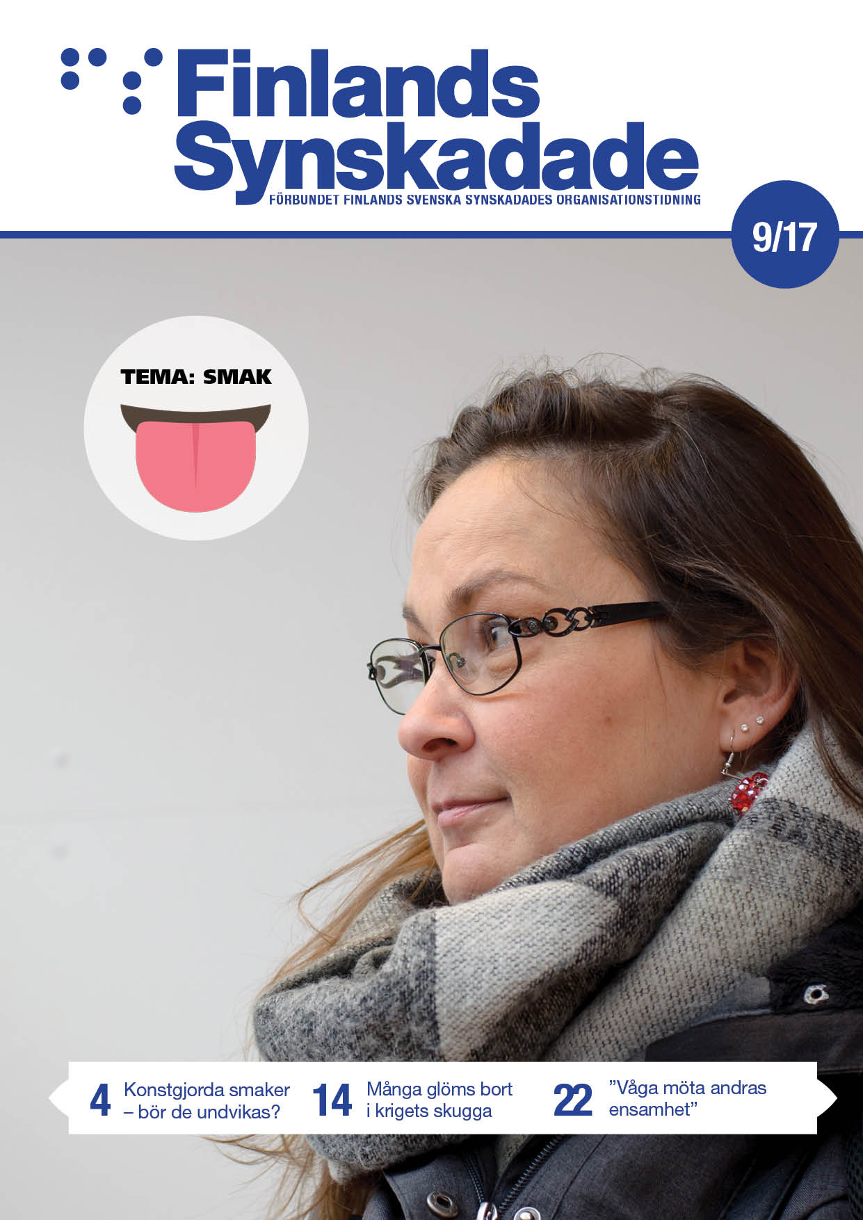 En brunhårig kvinna med stor grå skarf och glasögon tittar ut till vänster i bild.