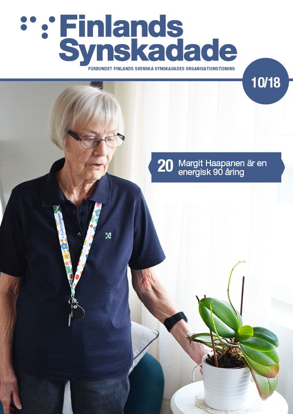 Margit Haapanen står vid fönstret och tittar på en grön orkidé