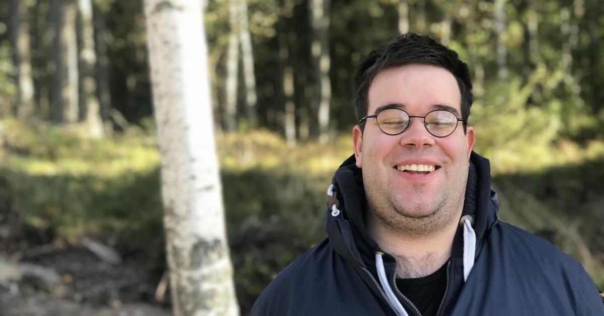 Fredrik Lindgren är utomhus klädd i mörk jacka, i bakgrunden ser man skog.