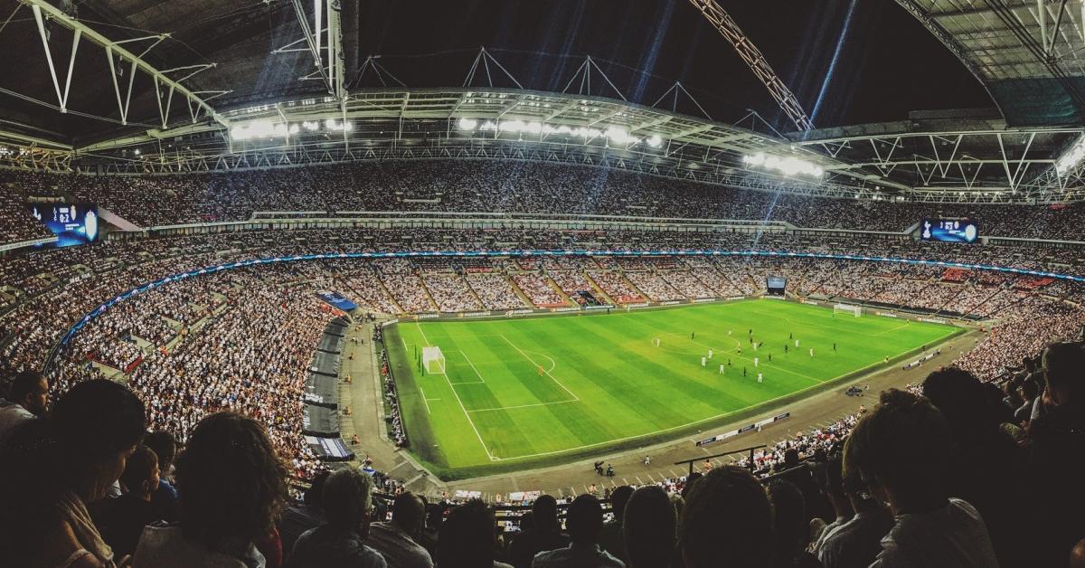 Ett upplyst fotbollsstadion och fullsatt publikläktare runt omkring.