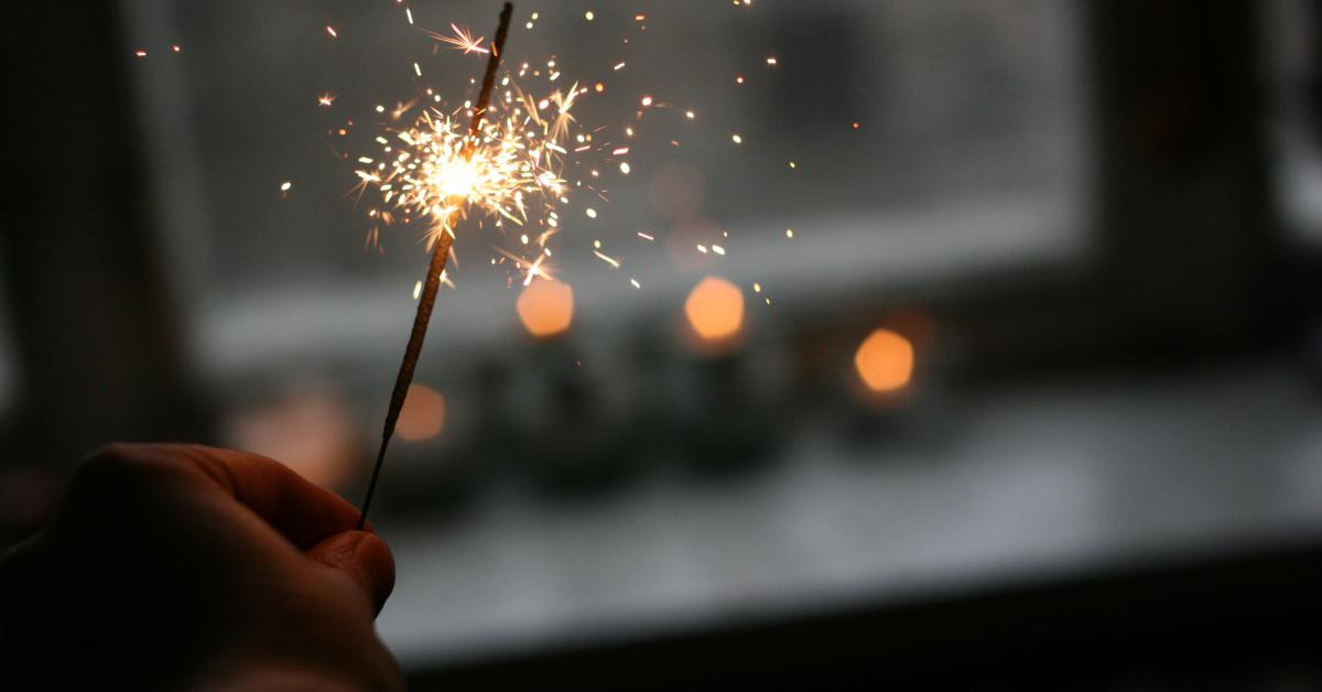 En hand håller i tomtebloss (sprakasticka).