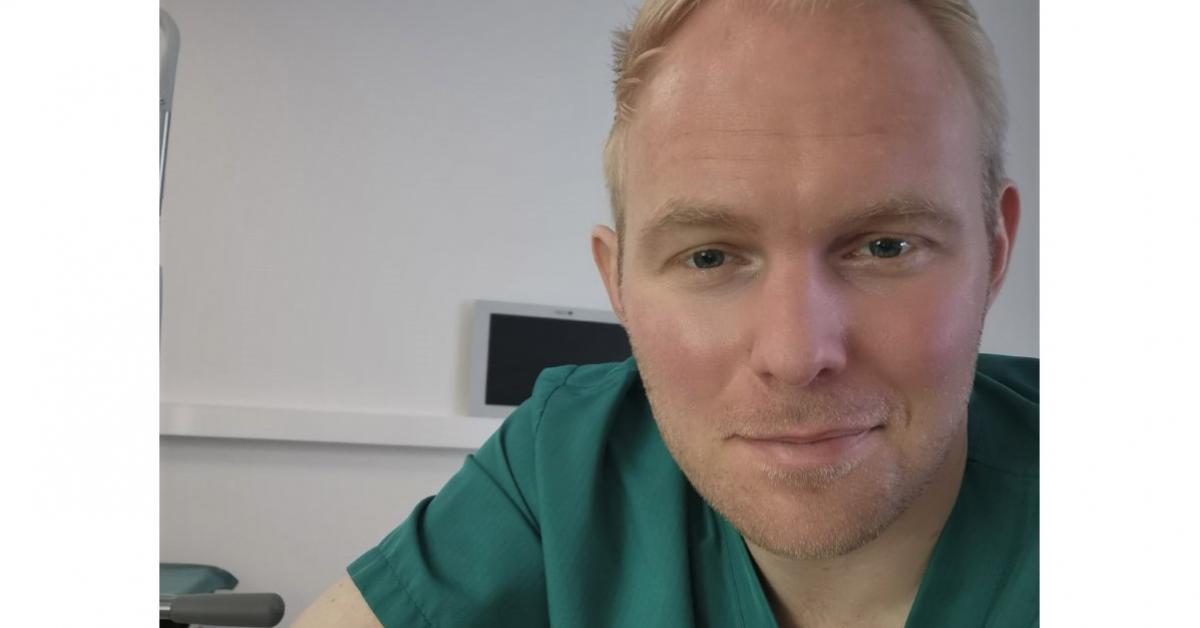 Henrik Bygglin har ljust kort hår och är klädd i en grön läkartröja. 