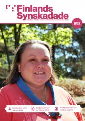 En brunhårig kvinna står i solskenet med en scouthalsduk runt halsen och gröna träd syns i bakgrunden