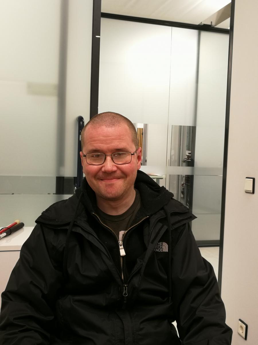 Petri Nokkala har kortsnaggat hår, glasögon och ler ett ihopbitet leende.